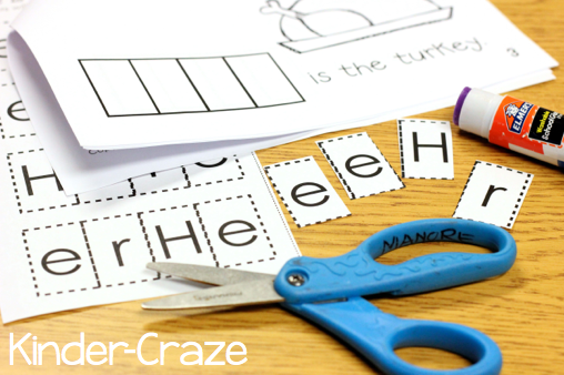 the letters of the word "here" are cut out on desk and are ready to glue into printable sight word book a scissors and glue stick sit next to them