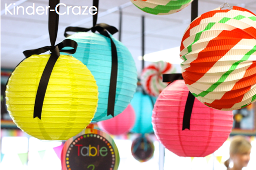 paper globe lanterns hanging in kindergarten classroom some offer bright pops of color while green, white, and red striped lanterns serve as holiday decor