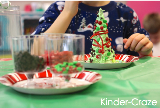 clear cups filled with treats for decorating sit in front of student and their decorated tree on a green table cloth