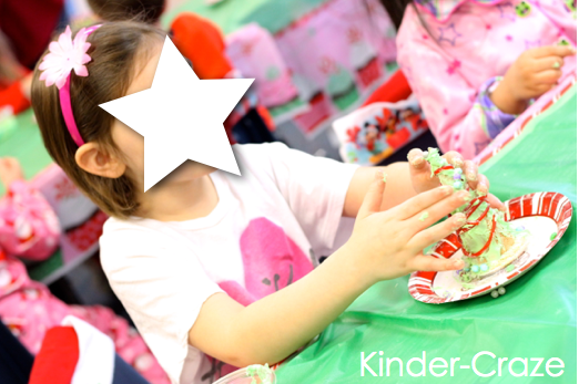 kindergartener pressing red and green candies into frosting on their tree