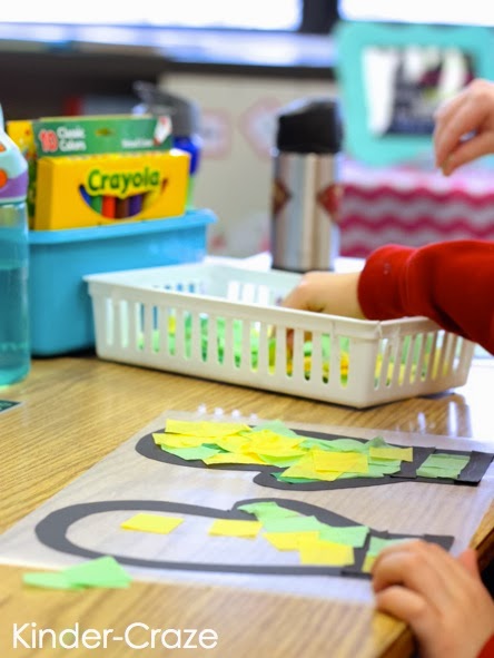 child at desk reaching into basket of green and yellow tissue paper squares to add to their window craft