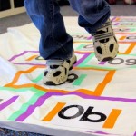 kindergartener skip counting by 10s as they play hopscotch on indoor mat