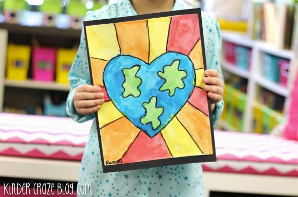 child holding up completed earth day art project in classroom