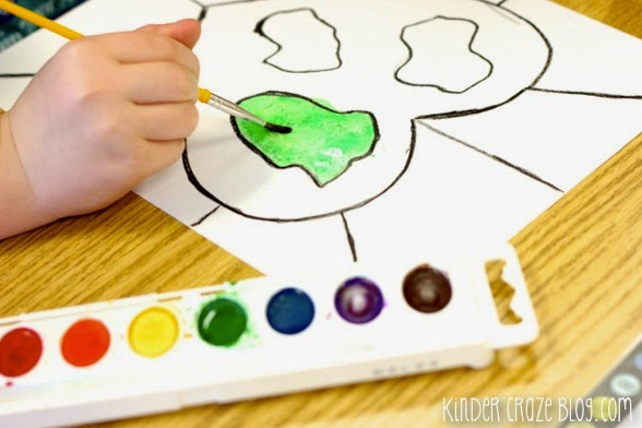 child using green watercolor paints for earth day art project