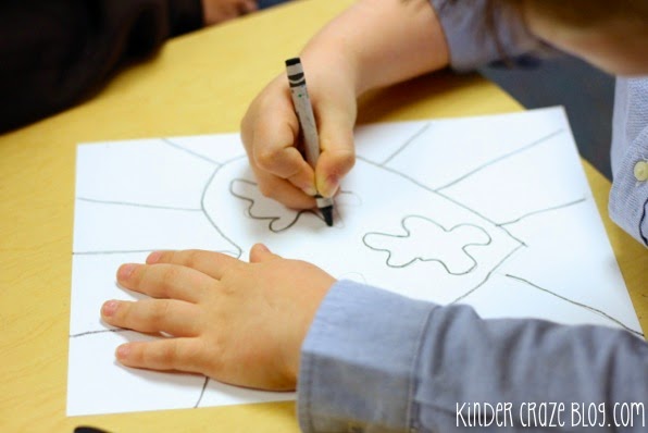 child using black crayon to trace heart-shaped earth drawing