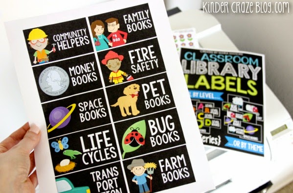 teacher holding full sheet of black classroom library labels with categories "community helpers, life cycles, family books, money books, fire safety, space books, pet books, bug books, transportation books, farm books"