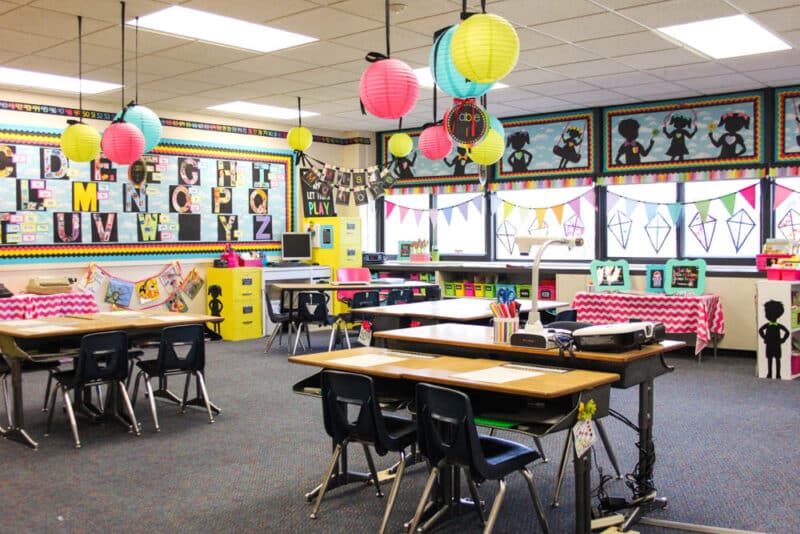 brightly colored kindergarten classroom with colorful lanterns hanging from the ceiling, silhouettes of children playing, and pops of pink and yellow