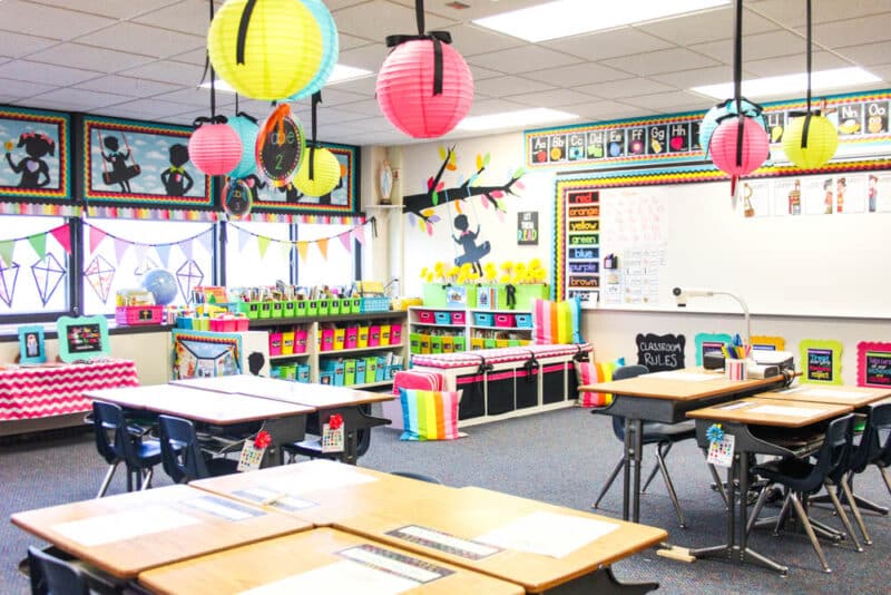 bright and colorful kindergarten classroom decorations with student desks grouped into tables and a colorful classroom library in the back