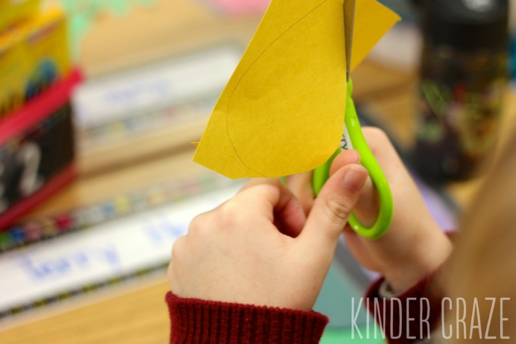 student using scissors to cut out yellow flame from construction paper for advent project