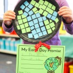 kindergarten student holding up a paper plate mosiac craft with "My Earth Day Promise" writing sheet attached in kindergarten classroom