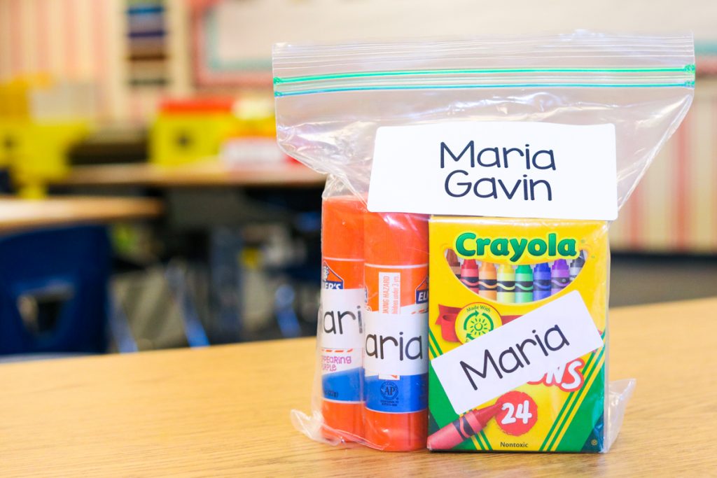 bag of school supplies on a table in a classroom. Supplies are placed in a ziploc bag and labeled with the name of the student