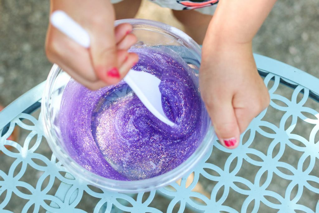 child mixing purple glitter slime at home