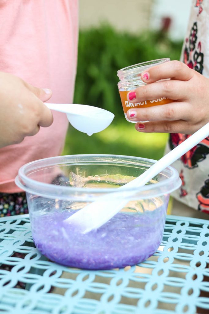 two children pouring baking soda to make glitter slime at home