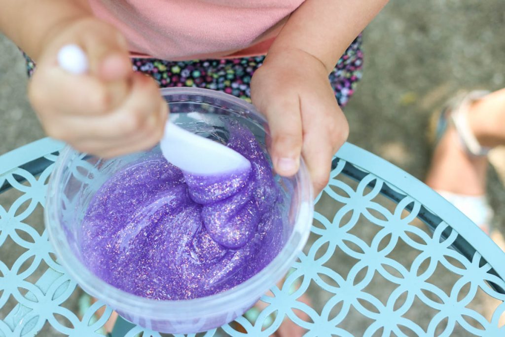 child mixing purple glitter slime at home from recipe