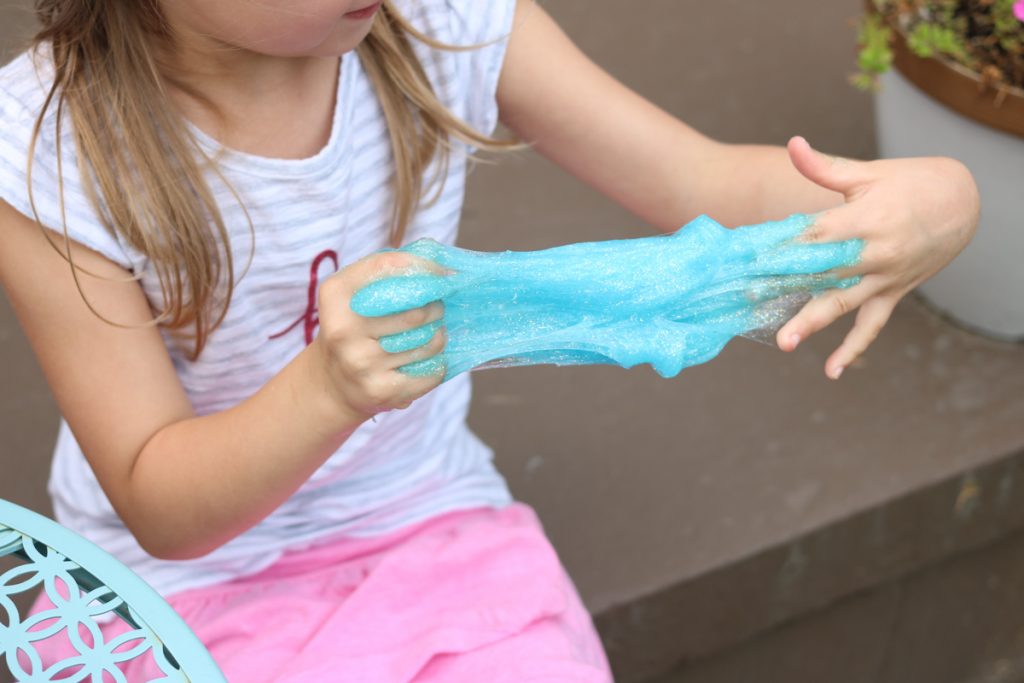 child pulling and stretching blue slime at home