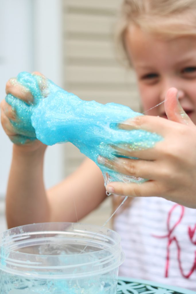 child stretching blue slime made at home