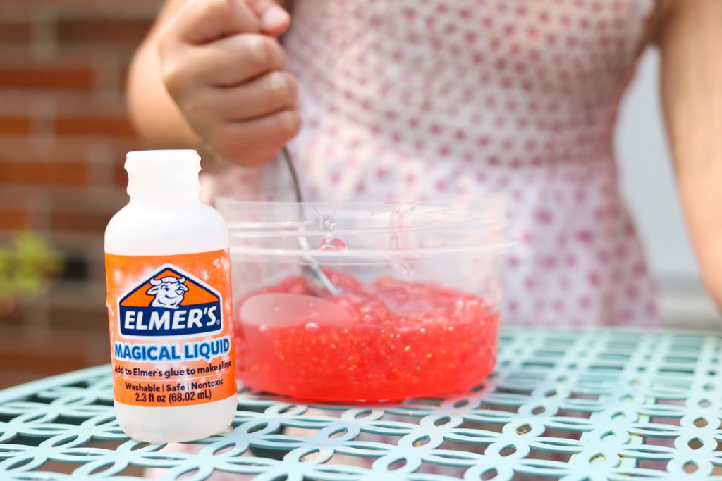 child stirring elmers magical liquid into red glitter glue