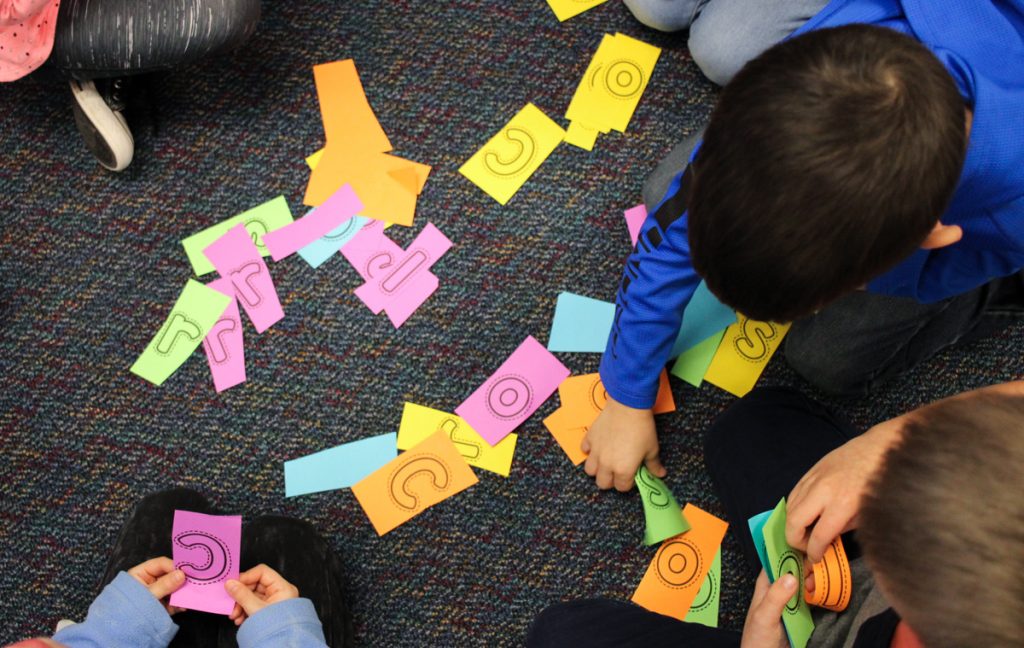 children unscrambling letters to spell color words in the classroom