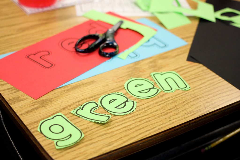green letters cut out and arranged on a classroom desk to spell color words