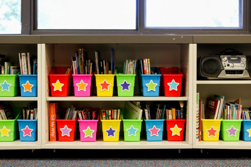 classroom library books neatly placed in brightly colored bins with rainbow star cutouts