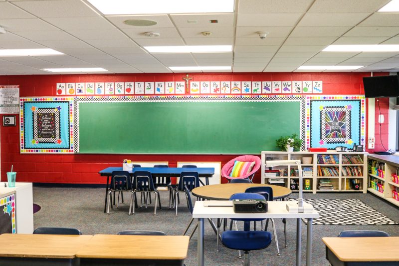 first grade classroom with bright red wall and classroom alphabet posters along the top of the chalkboard