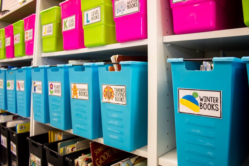 first grade classroom library with brightly colored bins that are labeled to identify which books are inside