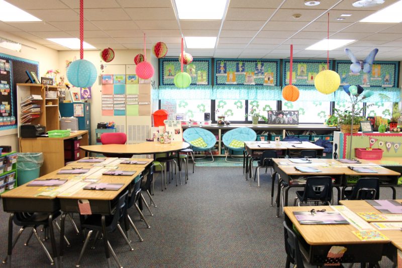 first grade classroom with desks arranged in tables and colorful lanterns hanging from the ceiling