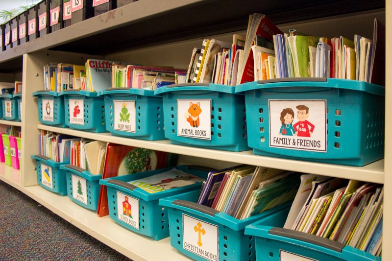 teal bins labeled and filled with books in a first grade classroom library