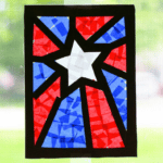 red, white and blue craft for kids displayed in window with sun shining though